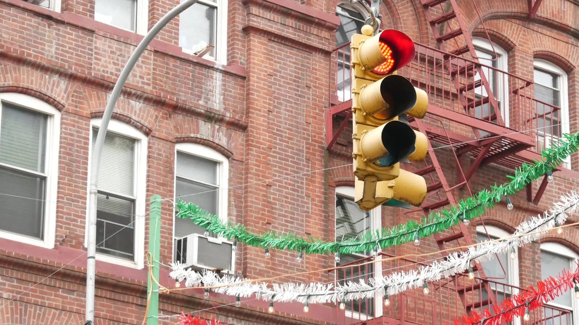 Red-brick buildings with fire escapes and red, white and green streamers over Mulberry Street in Little Italy, New York City
